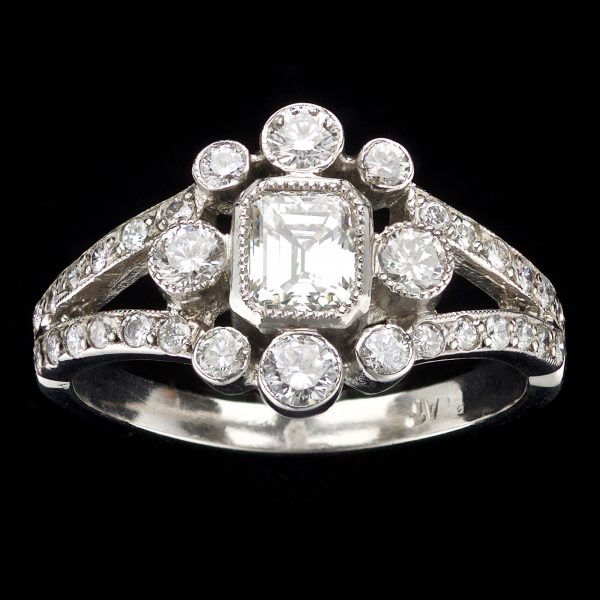 Diamond and platinum cluster ring set with a central emerald cut diamond 0.56ct L-M/VS1 surrounded by small diamonds total 0.76ct