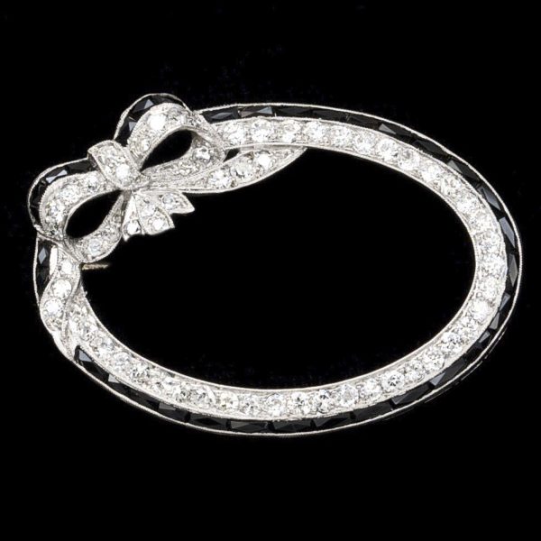 Art Deco oval diamond and onyx ribbon and bow brooch, platinum setting