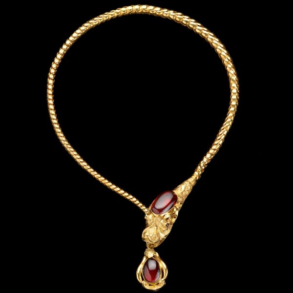 Antique gold articulated chain mythological dragon necklace, the head set with a large oval cabochon garnet, holding in its mouth a gold pendant set with a cabochon garnet. English c. 1870