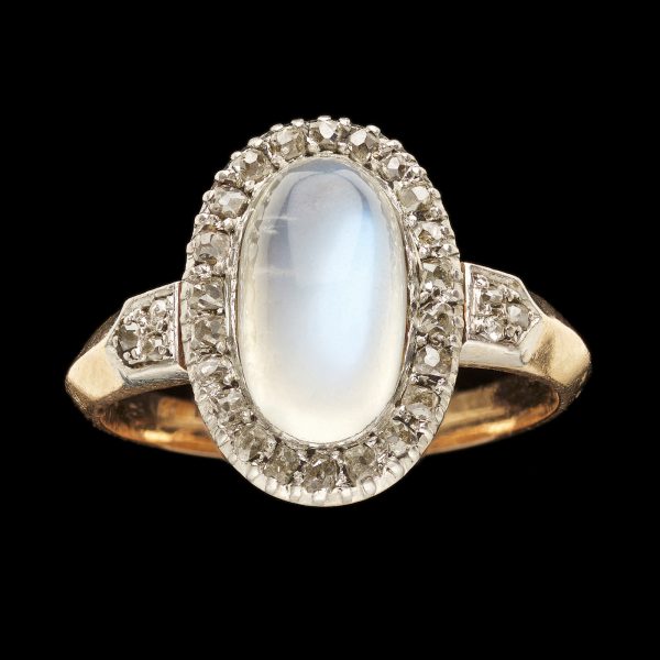 Victorian gold ring set with an oval moonstone surrounded by rose diamonds the shoulders also set with diamonds. Locket section at the back of the moonstone , English c 1960