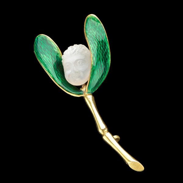 Brooch in the form of mistletoe leaves in green enamel, the berry a moonstone, carved with the head of a cherub. Attributed to Carlo Giuliano, circa 1890