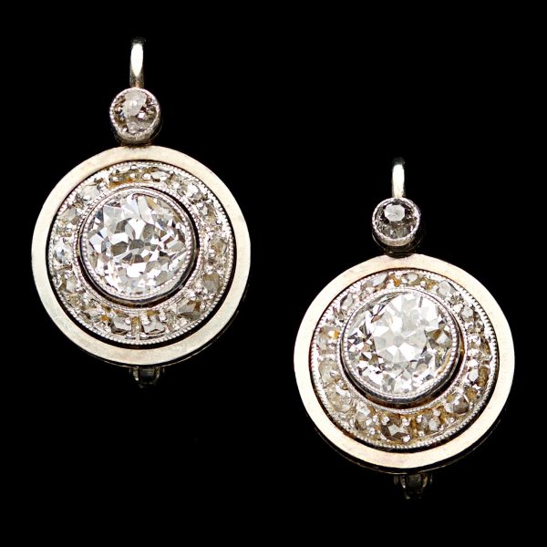 Edwardian diamond earrings each set with an Old European cut central diamond 0.65ct H-I colour, surrounded by small diamonds total 0.36ct